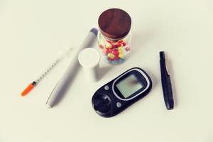 close up of glucometer, insulin pen and drug pills