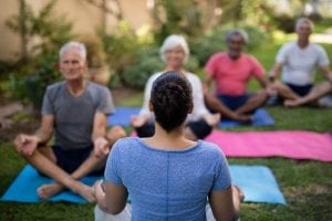 Trainer guiding senior people in meditating exercise